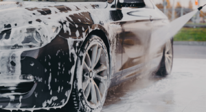 Carro sendo lavado com espuma durante processo de limpeza automotiva profissional