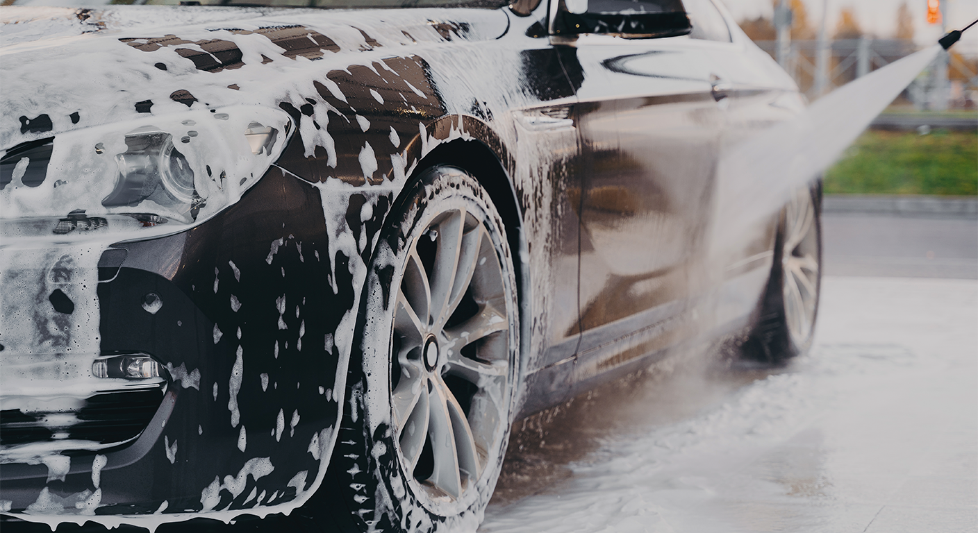 Carro sendo lavado com espuma durante processo de limpeza automotiva profissional